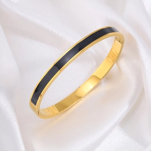 Detail van de gouden titanium armband met zwart emaille inlegwerk en scharniersluiting