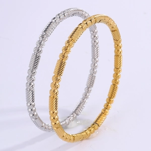 Close-up of gold and silver stainless steel bracelets with bead and textured cylinder design