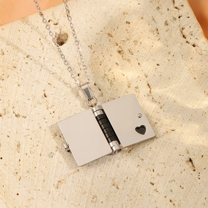 Détail d'un collier pendentif livre argenté ouvrable avec découpe cœur sur pierre