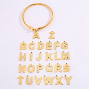 Detail van gouden gedraaide kabelarmring met een complete set van A-Z alfabet hangers