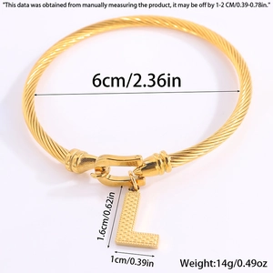 Detail van een gouden gedraaide kabelarmband met letter L hanger en hoefijzersluiting