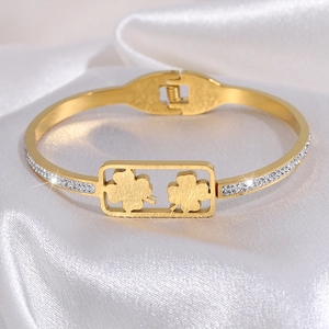 Macro-opname van gouden klaverarmband met ingelegde kristallen op wit satijnen achtergrond