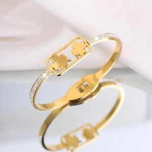 Detailopname van een gouden klaverarmband met kristalinleg en een handige veersluiting