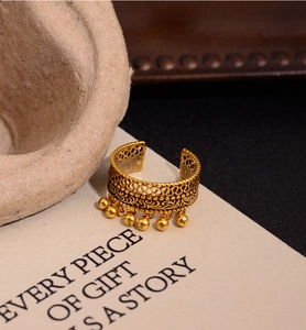 Detail view of retro gold lace hollow ring with dangling beads on artistic background