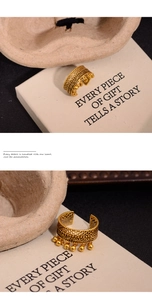 Macro detail of vintage gold hollow ring with five polished bead charms and ornate carving