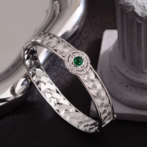 Intricate braided silver bracelet with a round green gemstone and zircon accents