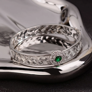 Chinese style silver open bangle with woven texture and a green gemstone focal point