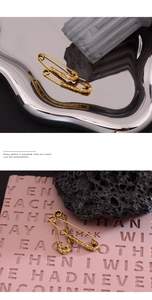 Detailansicht von zwei goldenen Vintage-Anstecknadeln mit floralem Relief auf Tablett