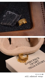 Detailed view of luxury gold hollow ring featuring delicate bead tassels and lace pattern