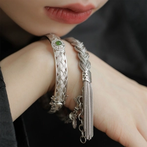 Détail d'un bracelet tressé argenté avec pierre verte et pendentif à franges