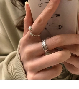 Close-up of irregular silver geometric rings with sphere and gear textures on finger