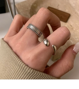 Close-up of irregular geometric silver rings with vintage stripes and open water drop design
