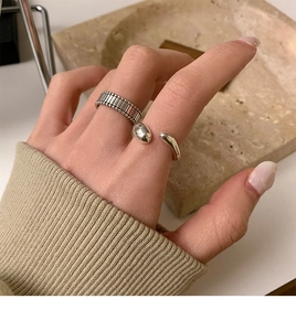 Detailed view of silver minimalist open ring and vintage striped band on finger