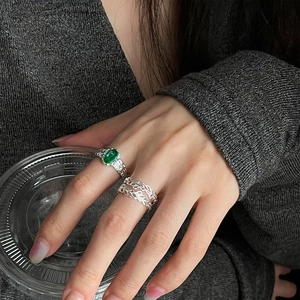 Set di anelli eleganti con gemma verde e piuma d'argento indossati su modella