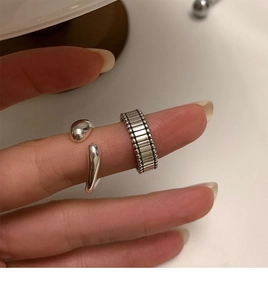 Macro detail of stacked vintage silver rings featuring vertical stripes and spherical tips