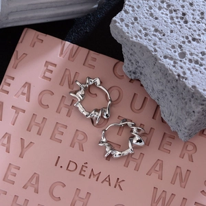 Chic silver spiral hoop earrings with liquid metal twist design on a textured stone display