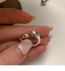 Close-up of irregular silver open ring with polished spherical ends and mirror finish