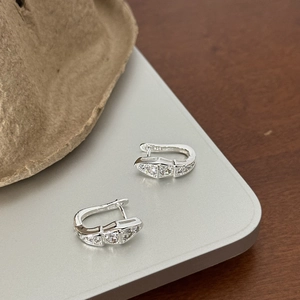 Silver snake hoop earrings with zircons and S925 hallmark on a minimalist surface