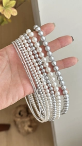 Comparaison détaillée de différentes tailles de perles blanches et grises avec la main