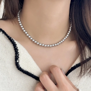 Gros plan d'un collier de perles argentées minimaliste porté au cou d'un mannequin