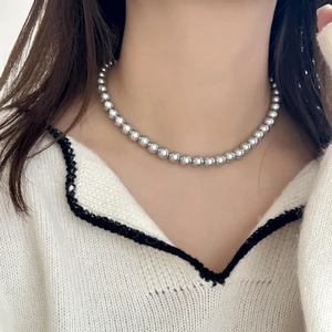 Collier ras du cou élégant avec perles argentées minimalistes sur un pull en maille