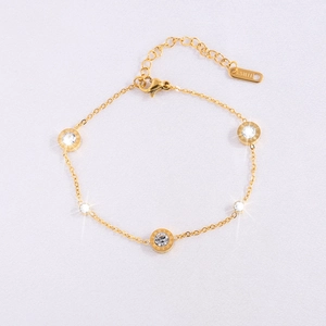 Macro detail of gold stainless steel bracelet with Roman numerals and zircon charms