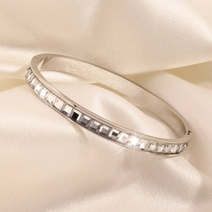 Silver stainless steel bangle with square-cut cubic zirconia inlays on satin background