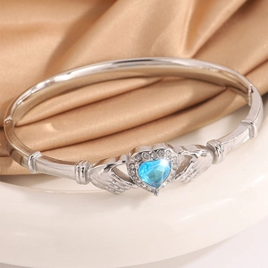 Macro shot of silver Claddagh bracelet with sky blue heart gemstone and diamond halo