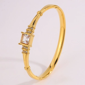 Detailed close-up of a gold-plated bangle with a central square zircon and side accents