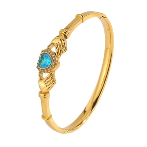 Gold Claddagh bangle featuring a blue heart-shaped gemstone with pave zircon accents