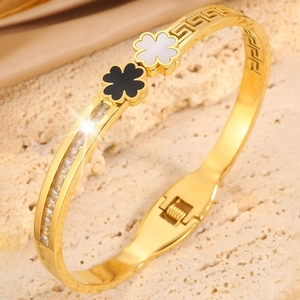 Close-up of golden clover bangle with enamel inlays, meander engraving, and zircon stones