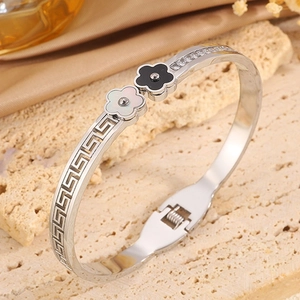 Detail of silver steel bracelet with zircon inlay and black and white flower charms