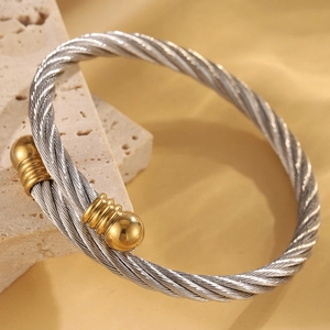Vue détaillée du bracelet câble en acier torsadé avec embouts sphériques dorés