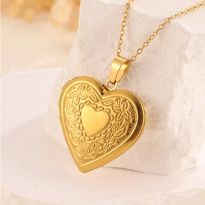 Nahaufnahme des goldenen Herzmedaillons mit Vintage-Blumenprägung an einer feinen Kette