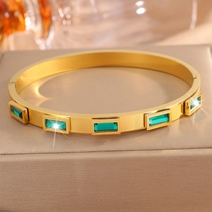 Dettaglio del bracciale in acciaio dorato 18K con incastonate pietre verde smeraldo