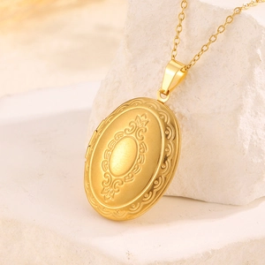 Detailaufnahme eines ovalen goldenen Medaillons mit kunstvollen floralen Vintage-Gravuren