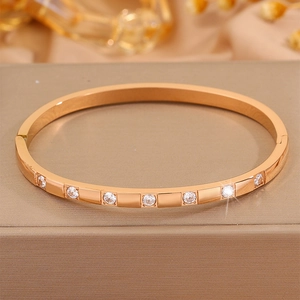 Close-up of rose gold stainless steel bangle with seven inset zircons on leather box