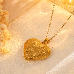 Makroaufnahme einer Vintage-Herz-Medaillon-Halskette mit floraler Gravur und Goldfinish