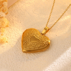 Makro-Detail des Vintage-Herz-Medaillons in Gold mit floraler Gravur auf der Oberfläche