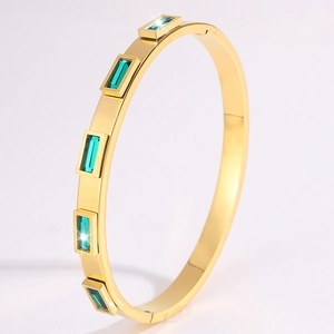 Dettaglio del bracciale in acciaio dorato con pietre rettangolari verde smeraldo