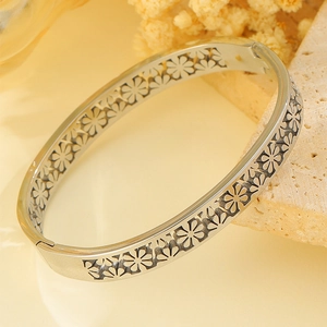 Nahaufnahme von silbernen Gänseblümchen-Mustern auf einem polierten Edelstahl-Armband