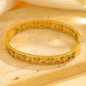 Detail eines hohlen Gänseblümchenmusters auf einem polierten Gold-Edelstahlarmreif