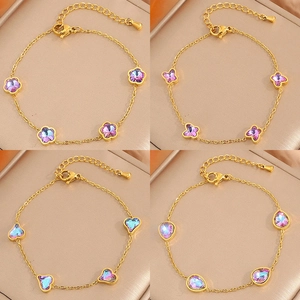 Quatre bracelets en acier inoxydable doré avec breloques fleur, papillon, cœur et goutte