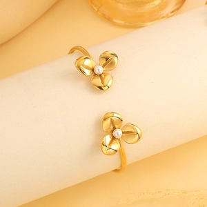 Detail van gouden roestvrijstalen open armband met bloemmotieven en witte parels