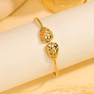 Detail van de gouden roestvrijstalen open armband met geweven druppelvormige uiteinden