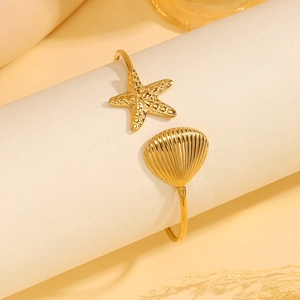 Detailopname van een gouden roestvrijstalen armband met een zeester en een schelpenkap