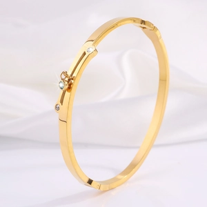 Close-up of gold titanium steel bangle featuring micro-inlaid diamonds on white silk
