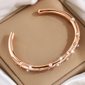 Detailopname van een roségoudkleurige armband met parels en schitterende kristallen