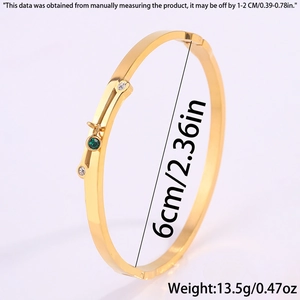 Detail view of gold titanium bangle featuring a green gemstone and side buckle closure