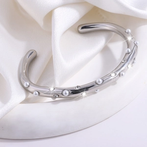 Detailopname van een zilveren C-stalen armband met parels en ingelegde strassteentjes